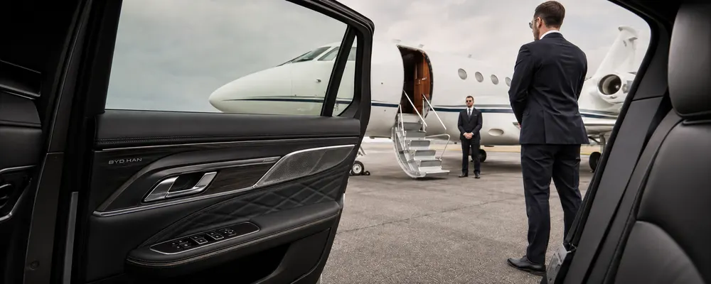 A chauffeur greeting a passenger beside a private jet